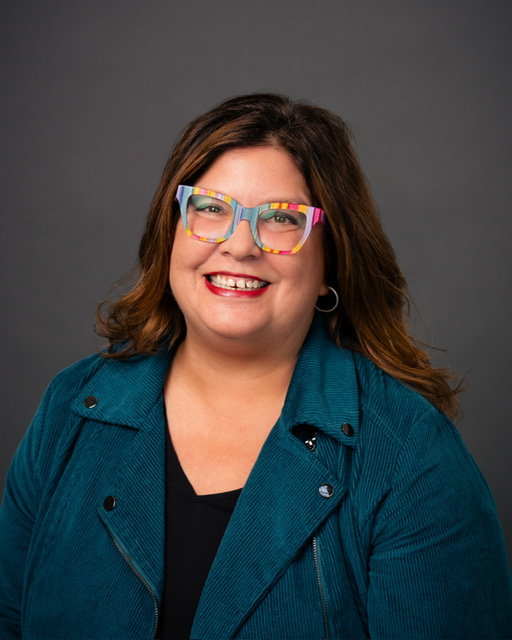 Author portrait of Natalia Lee in a blue jacket and signature rainbow gradient-lined glasses. Image permission given to Onward Sister by Natasha Parvey.